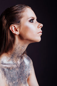 Close-up of young woman against black background