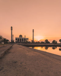 Scenic view of lake by buildings against orange sky