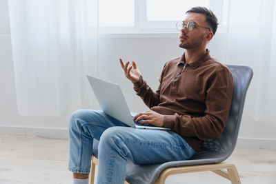 Young man using laptop while sitting on sofa at home