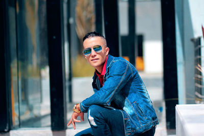 Portrait of young man wearing sunglasses sitting outdoors