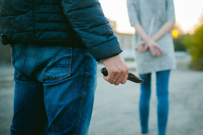 Rear view of man standing with knife against woman