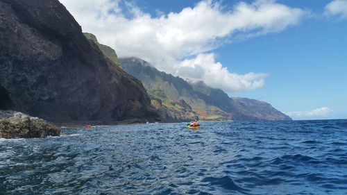 Scenic view of sea by mountain against sky