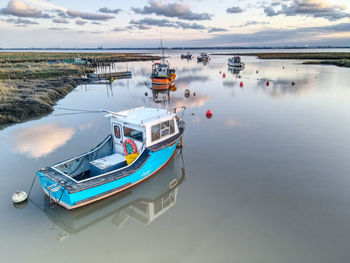 Fishing boats moored in sea against sky