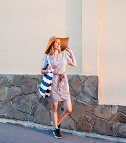 Full length of woman standing against wall