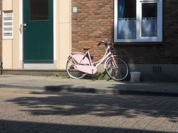 Bicycle parked on footpath against building