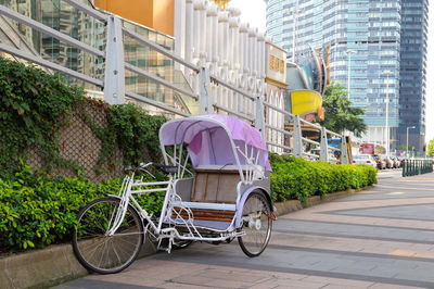 Bicycle by street against buildings in city