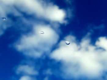 Low angle view of raindrops on blue sky