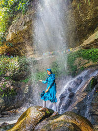 Woman standing by waterfall in forest