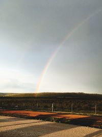 Scenic view of rainbow over field against sky