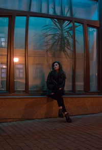 Full length of young woman looking away while sitting outdoors