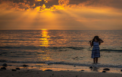 Full length of girl standing at beach during sunset