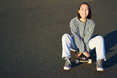 Portrait of young woman sitting on road