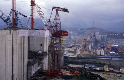 Cranes at commercial dock against sky