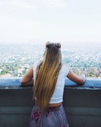Rear view of woman standing on retaining wall against sky