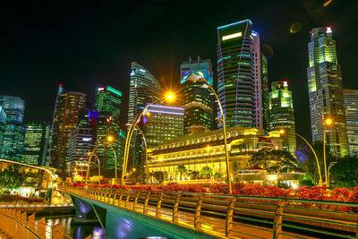 Illuminated bridge and buildings against sky at night