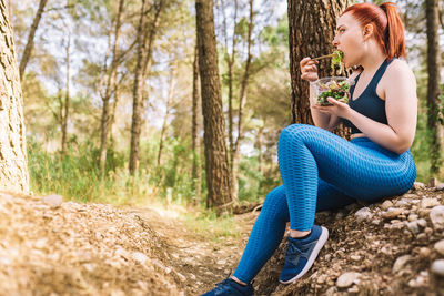 Young woman eating salad in forest