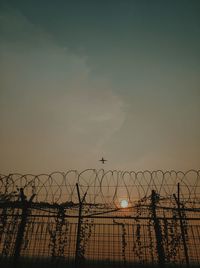 Low angle view of silhouette fence against sky during sunset