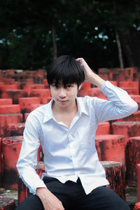 Portrait of man sitting on red tree stump