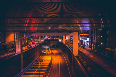 Illuminated bridge over road in city at night