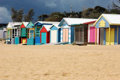 Colorful beach huts by trees against sky