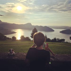 Rear view of boy standing by retaining wall against lake