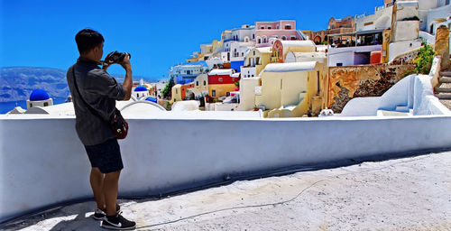 Full length rear view of woman photographing cityscape