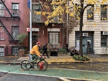 Man riding bicycle on street against buildings in city