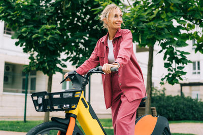 A young woman uses an urban rented electric bike. green energy.