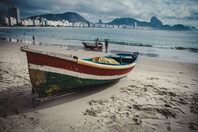 Boats moored on beach against sky