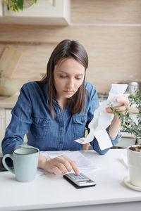 Worried woman calculating bills at home