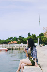 Side view of woman sitting on lake