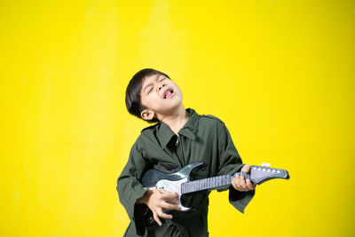 Full length of teenage girl standing against yellow wall