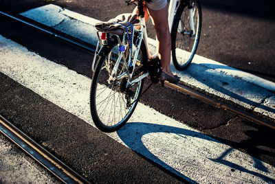 Low section of woman riding bicycle while crossing city street