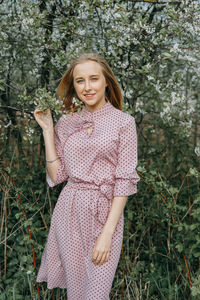 Blonde girl on a spring walk in the garden with cherry blossoms. female portrait, close-up. 