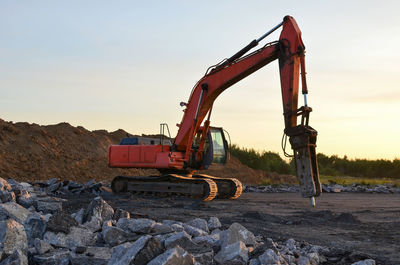 Construction site on shore against sky during sunset