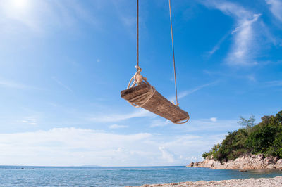 Swing hanging at beach against blue sky