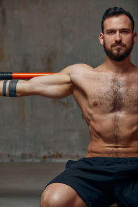 Shirtless man exercising against wall