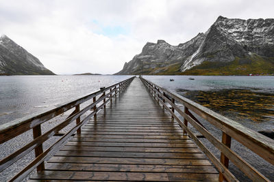 Wooden bridge pier at the coast against sky  in moskenesoya during winter in lofoten norway