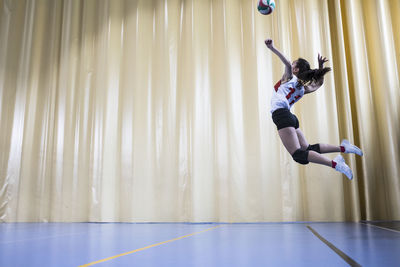 Professional female volleyball player in action serving ball