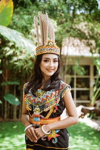 Portrait of young woman standing against trees