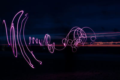 Illuminated light painting against sky at night