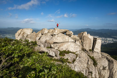 People on rocks by mountain against sky