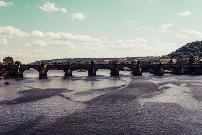 Bridge over river in city against sky