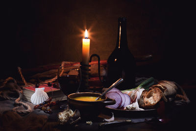 Close-up of illuminated candle by food on table