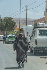 Rear view of man walking on road in city