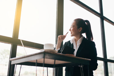 Young woman looking away while sitting on table