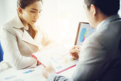 High angle view of colleagues discussing at desk in office