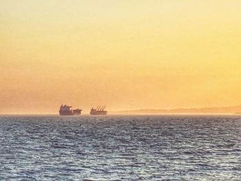 Ship sailing on sea against clear sky during sunset