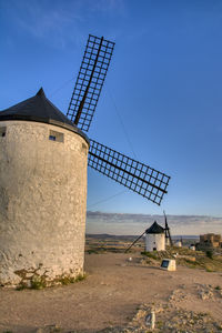 Traditional windmill on field against blue sky