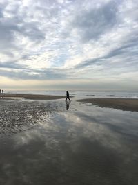 Silhouette man standing on beach against sky